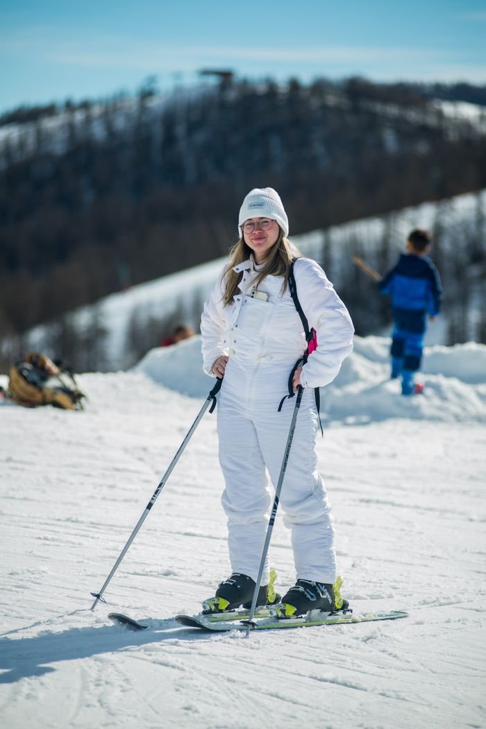 Local Ski Resorts: Find the Perfect Slopes for Your Next Adventure Woman in ski-wear enjoying a sunny day on a snowy mountain slope with ski poles.